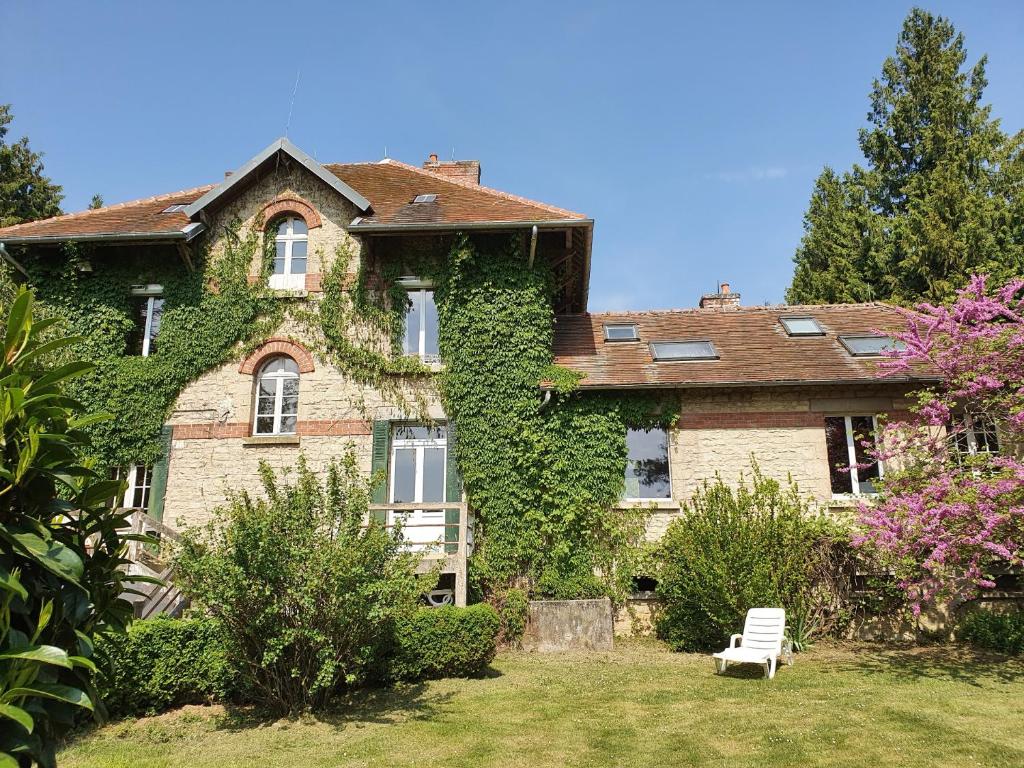 uma casa coberta de hera com um banco branco à sua frente em Gîte de la Bove em Bouconville-Vauclair