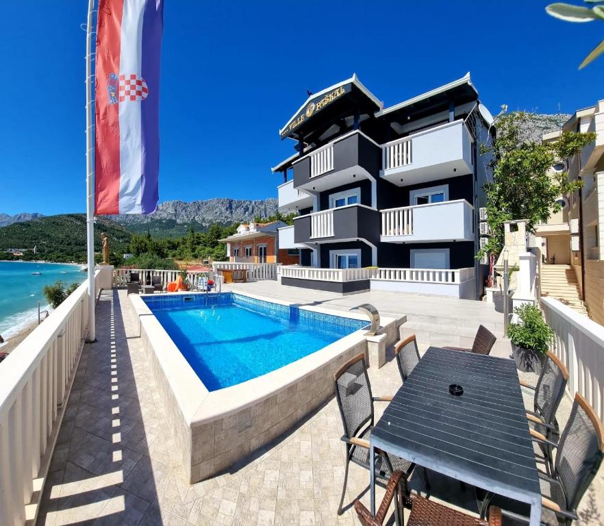 a building with a pool and a table next to it at Guesthouse Villa Paškal in Zaostrog