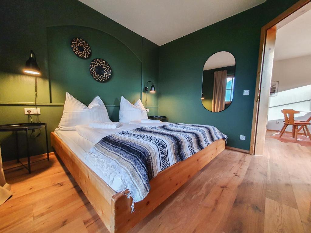 a bedroom with a large bed with a green wall at Gruberwirt Apartments in Innsbruck