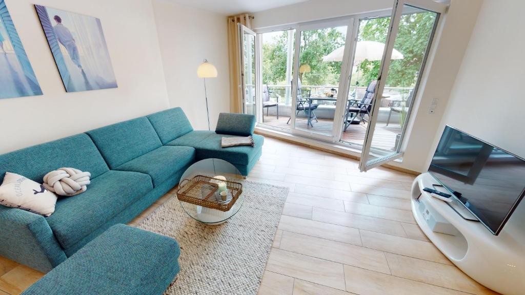 een woonkamer met een blauwe bank en een tv bij Villa Meeresrauschen Wohnung 09 - Lieblingsplatz in Pelzerhaken