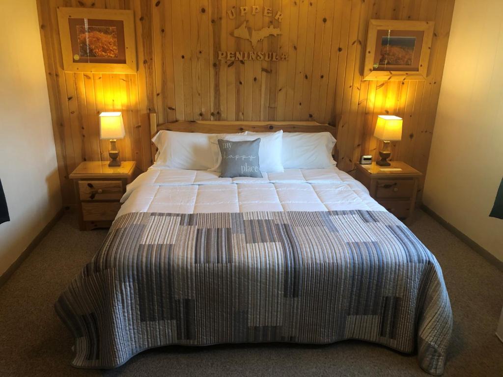 ein Schlafzimmer mit einem großen Bett mit zwei Nachttischen in der Unterkunft Holiday Motel in Manistique
