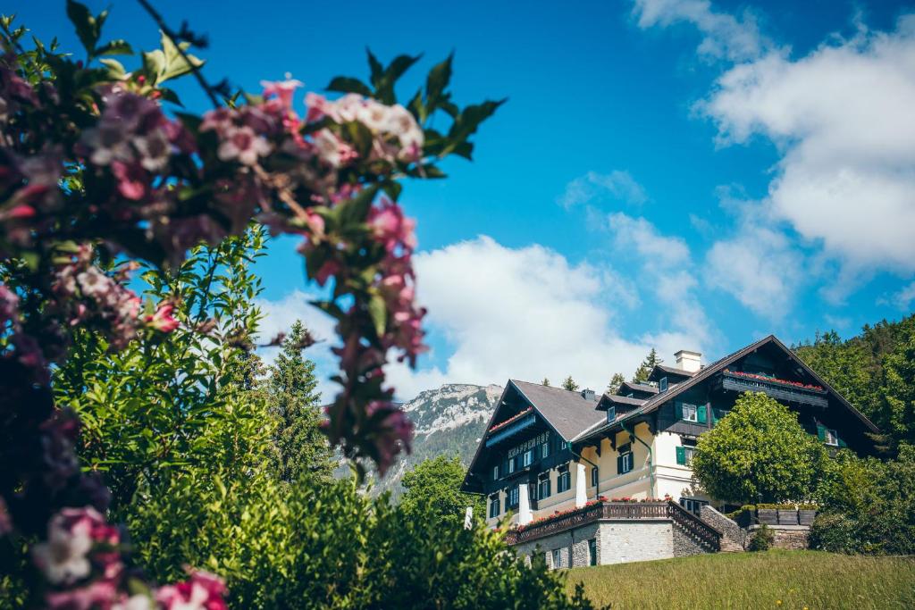ein Haus auf einem Hügel mit Blumen in der Unterkunft Der Knappenhof - Hotel & Restaurant in Reichenau