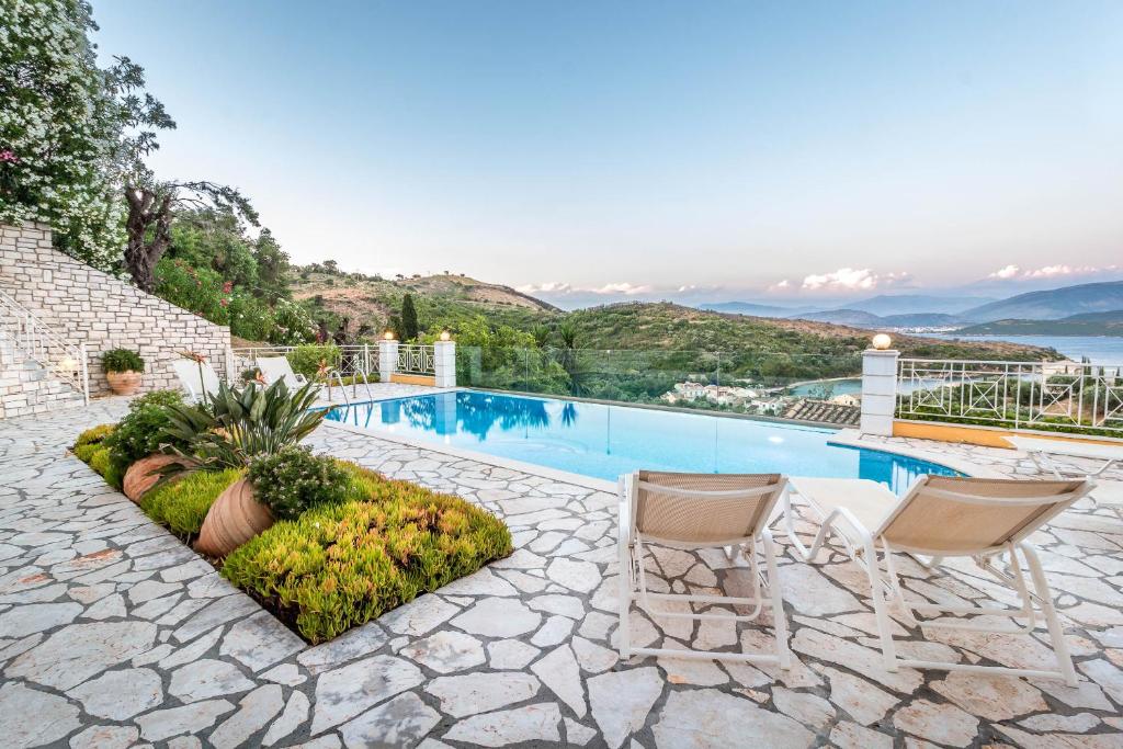 a house with a swimming pool with two chairs at Agios Stefanos Bay - Villa Maria in Ágios Stéfanos