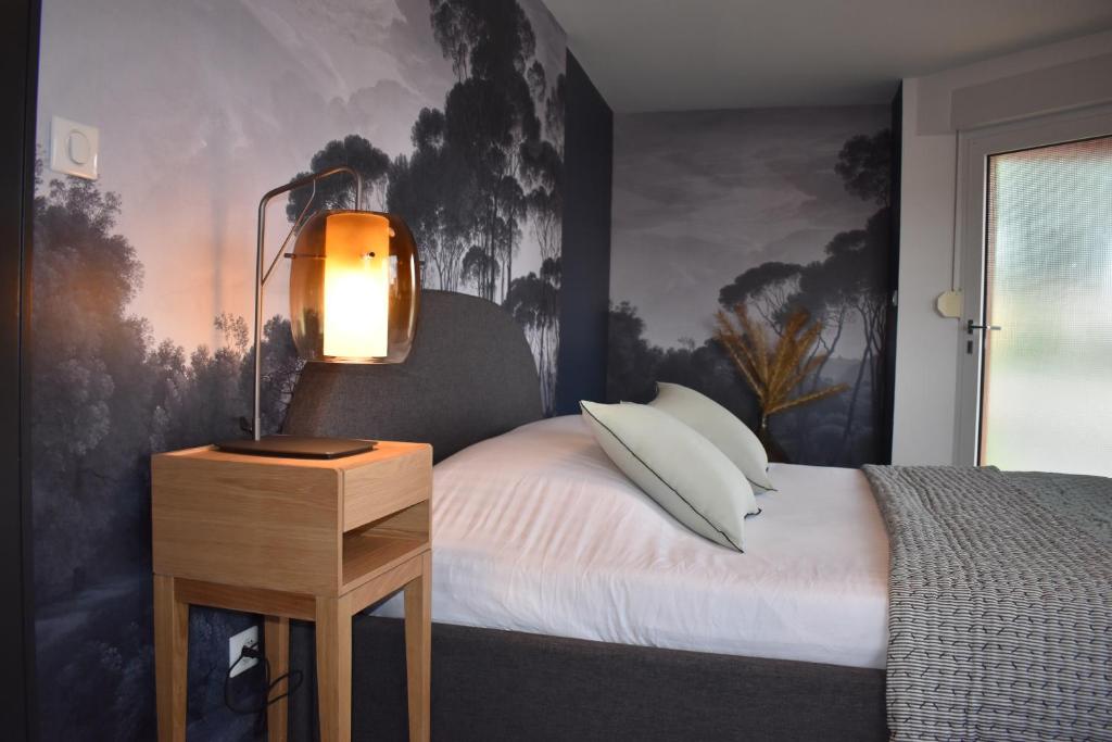 a bedroom with a bed with a lamp on a table at Chez Max Alsace in Saint-Hippolyte