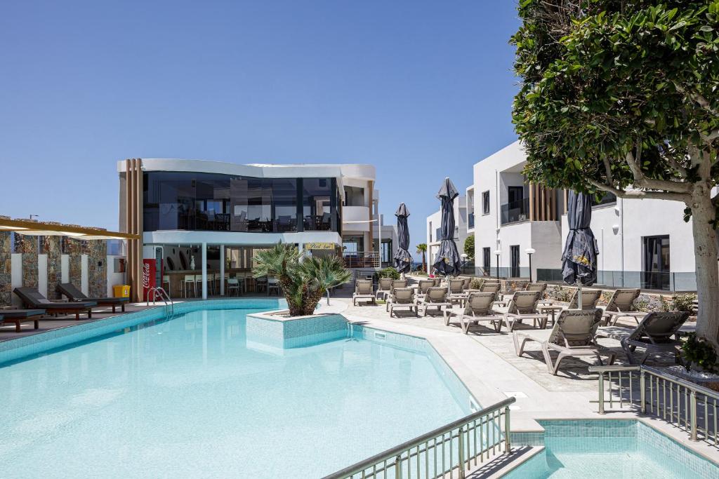 a large swimming pool with chairs and a building at Golden Bay Boutique Hotel & Bungalows in Kokkíni Khánion