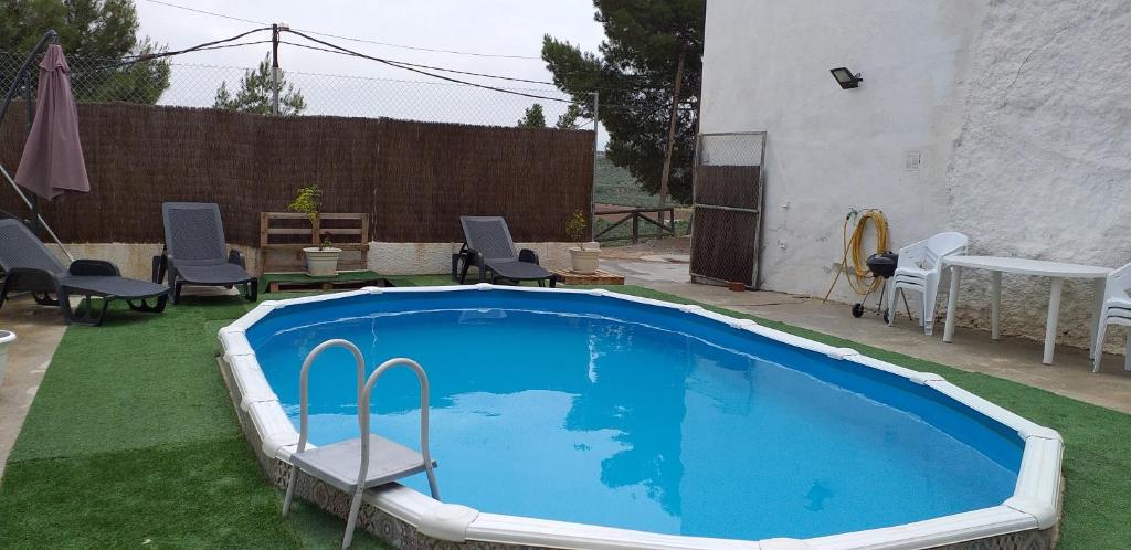 uma piscina num quintal com cadeiras e uma mesa em Casa Cueva Sol em Pozo Alcón