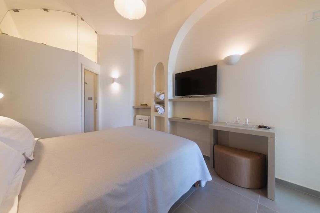 a bedroom with a white bed and a television at Insula Boutique Hotel in Procida