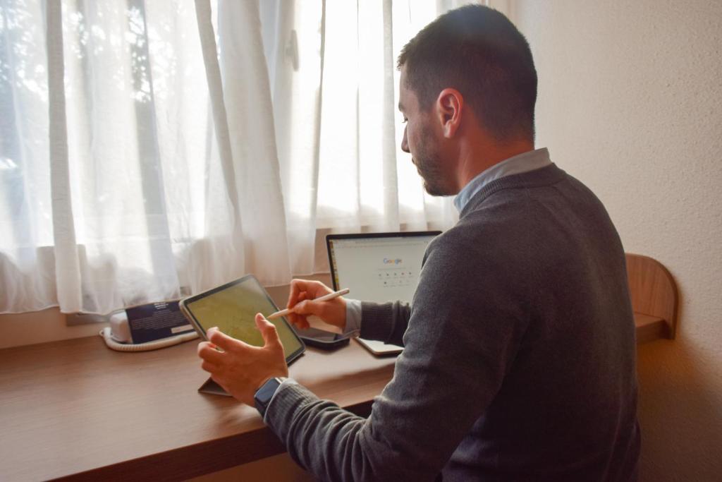 un hombre sentado en un escritorio usando una tablet en Campanile Millau, en Millau