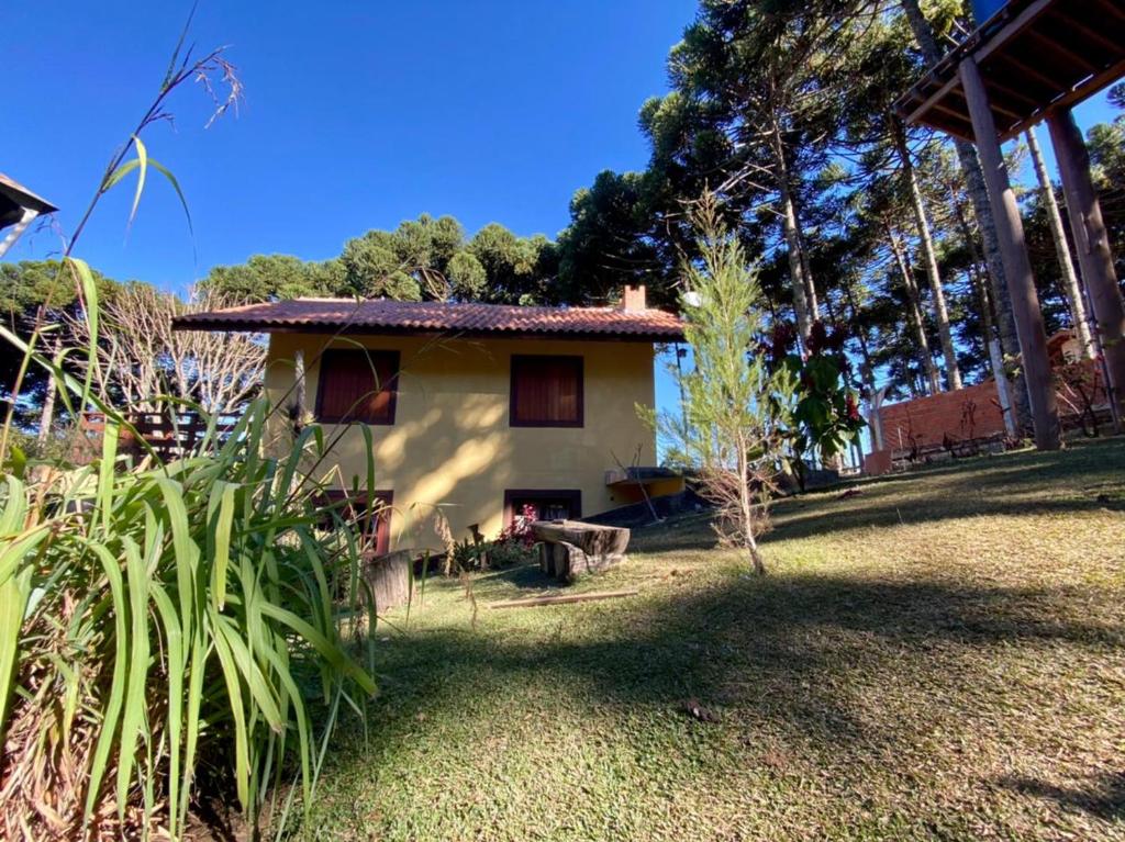 a small house in a yard with trees and grass at Chalé vale das Araucárias in Monte Verde