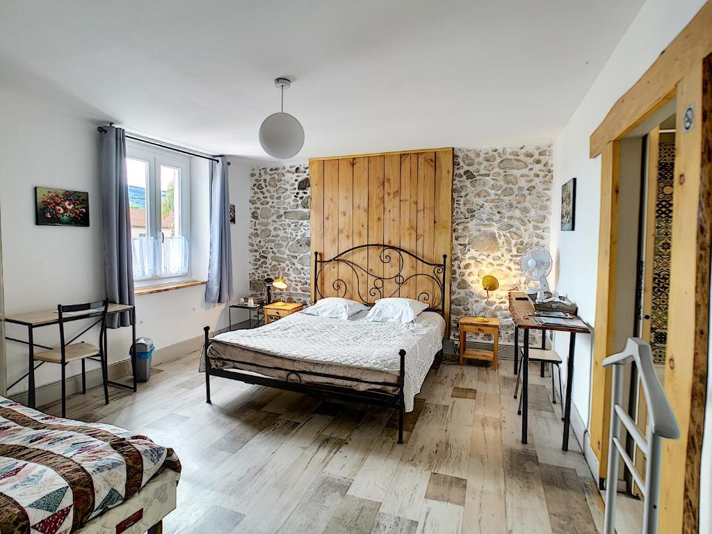 sypialnia z łóżkiem i kamienną ścianą w obiekcie Maison de ville au pied de la Montagne Noire w mieście Mazamet