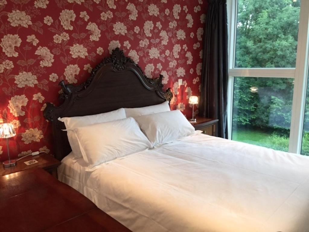 sypialnia z białym łóżkiem i czerwoną ścianą w obiekcie City Centre Luxurious Cambridge 2 Bed Apartment with Balcony, Lift, Free Parking, Fast WIFI & Sleeps 6 w Cambridge