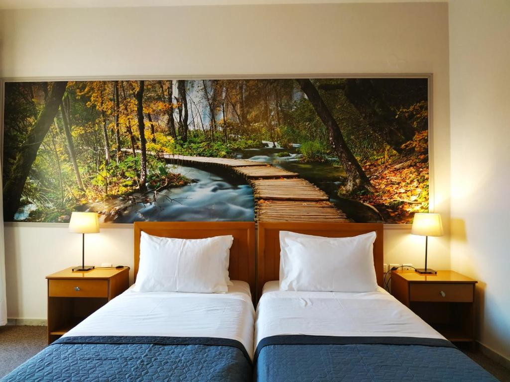 two beds in a hotel room with a painting on the wall at Eviali Apartments in Limne