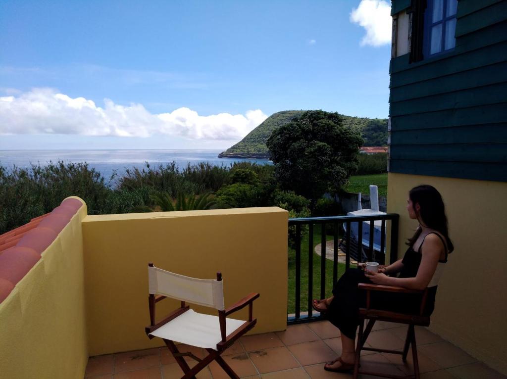 Una donna seduta su un balcone che guarda l'oceano di Varandas Miramar ad Angra do Heroísmo