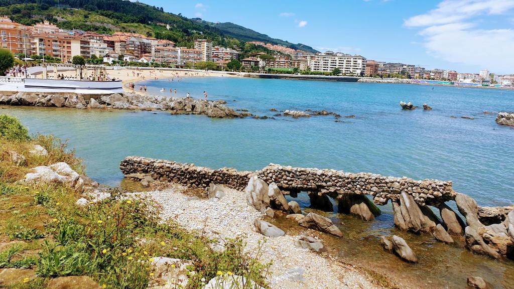 a beach with a bunch of rocks in the water at Castro Urdiales in Castro-Urdiales