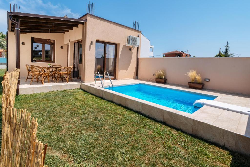 un patio trasero con piscina y una casa en SALVE holiday houses, en Paralia Katerinis