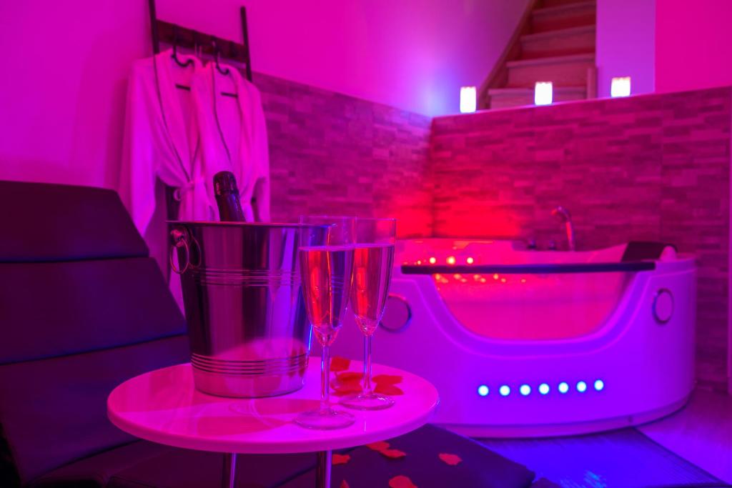 two glasses on a table in a room with a tub at Love Room - Suite romantique avec spa privatif in Le Puy en Velay