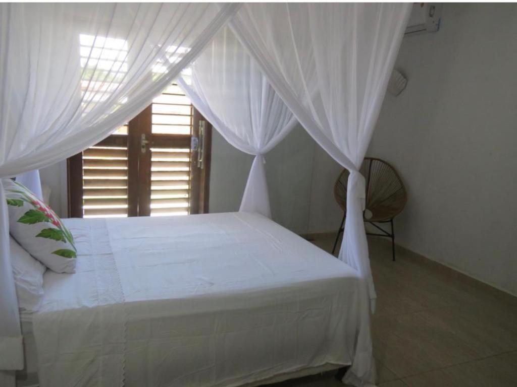 sypialnia z łóżkiem z białymi zasłonami i oknem w obiekcie Concept House Caraiva w mieście Caraíva