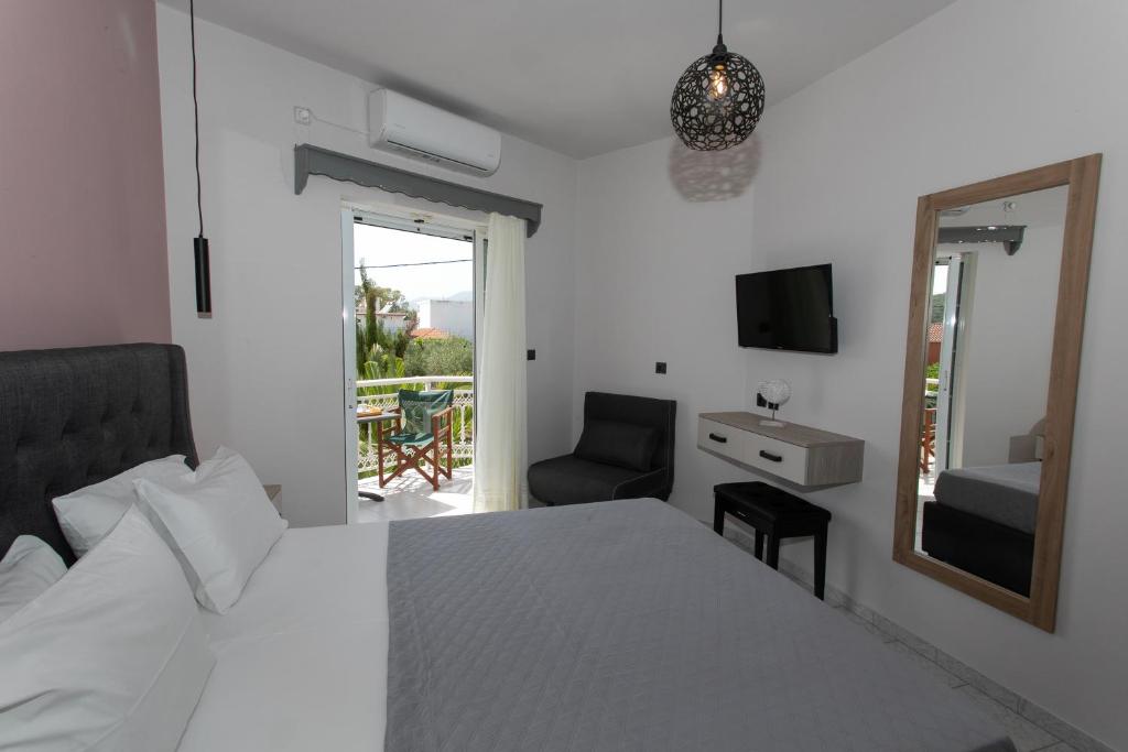 a bedroom with a bed and a mirror and a chair at Corali Studios in Ammoudia