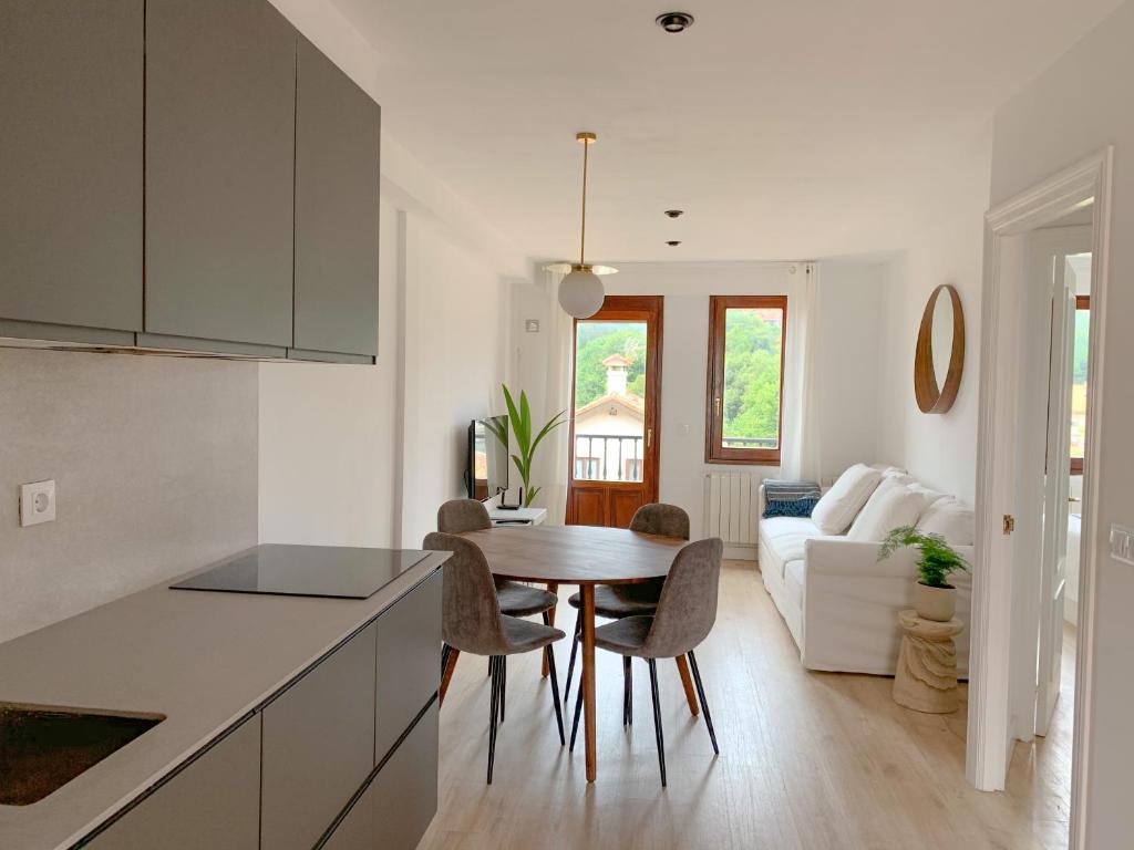 cocina y sala de estar con mesa y sillas en ACOGEDOR APARTAMENTO CON TERRAZA Y PARKING Publico EN COMILLAS, en Comillas