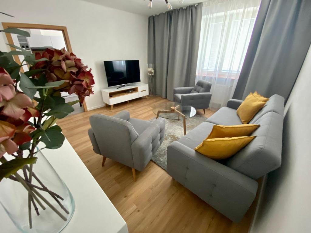 ein Wohnzimmer mit einem Sofa, 2 Stühlen und einem TV in der Unterkunft Apartment Poruba GARDEN VIEW in Ostrava