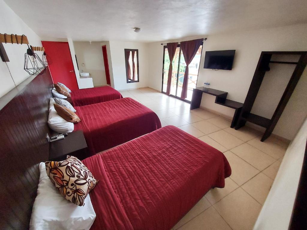 a hotel room with two beds and a flat screen tv at Hotel Sierra Linda in Xilitla