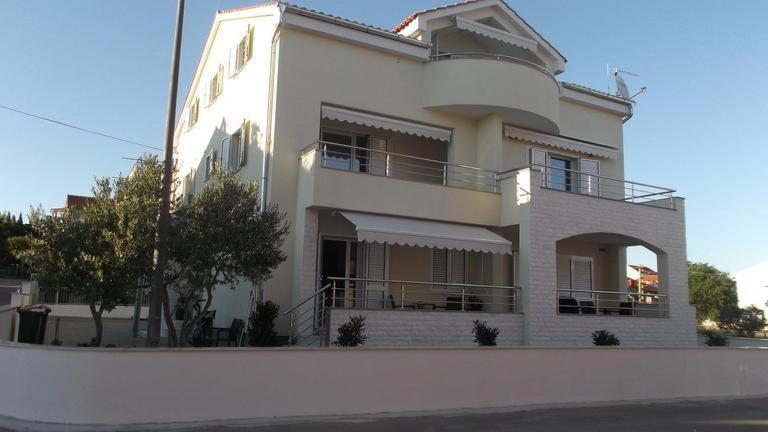 Une grande maison blanche avec balcon est située dans une rue. dans l'établissement White Anchor, à Vodice
