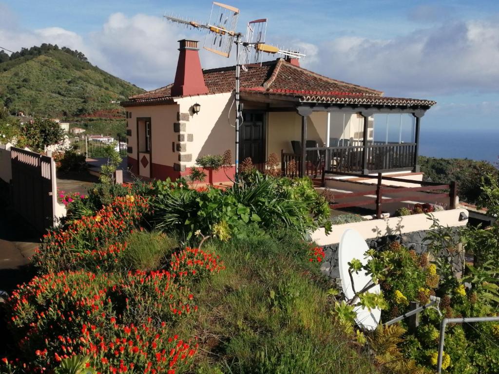 a house with a red chimney on a hill with flowers at Casa Rural La Florida in Barlovento