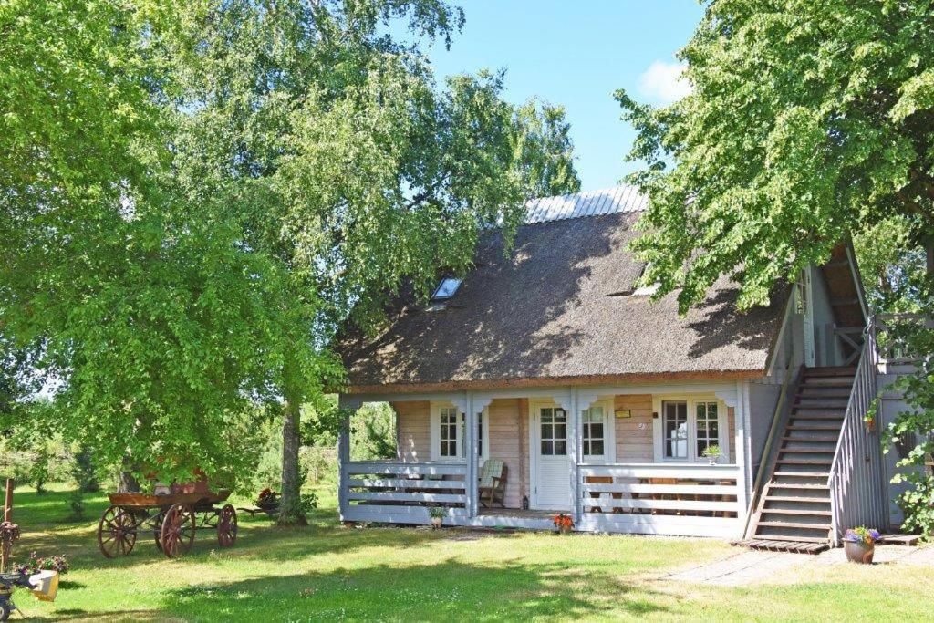 a small white house with a porch and trees at Judbidzi in Pape