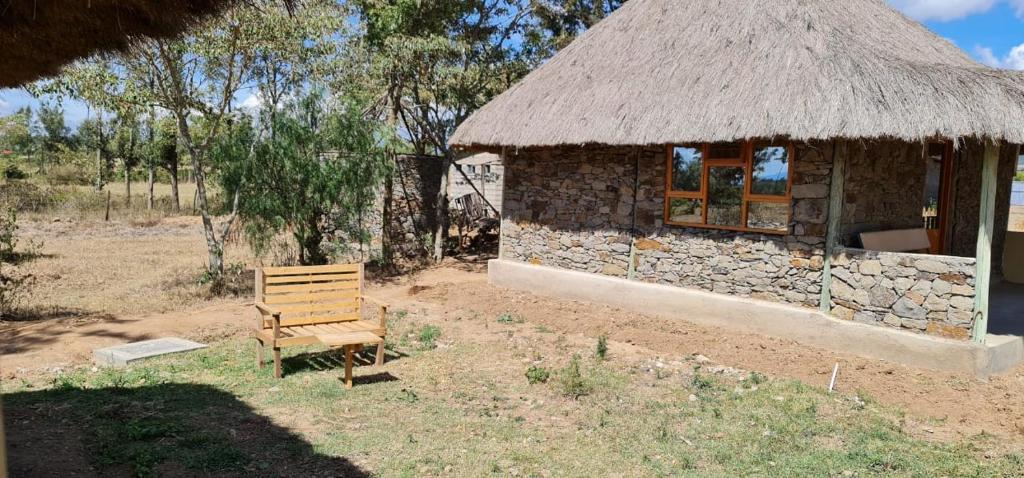 a small building with a straw roof and a bench at Le Tai Village Resort near Solio Game Reserve in Mweiga