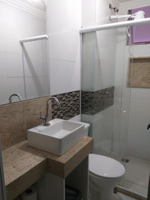 uma casa de banho branca com um lavatório e um WC em Ap Privativo Jockey, uma quadra da praia, Sentir-se em casa! em Vila Velha