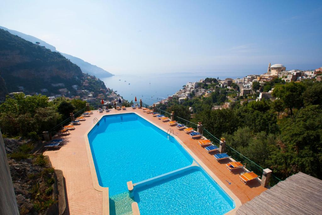 uma vista para uma piscina com cadeiras e para o oceano em Estate4home - RELAXING POSITANO em Positano