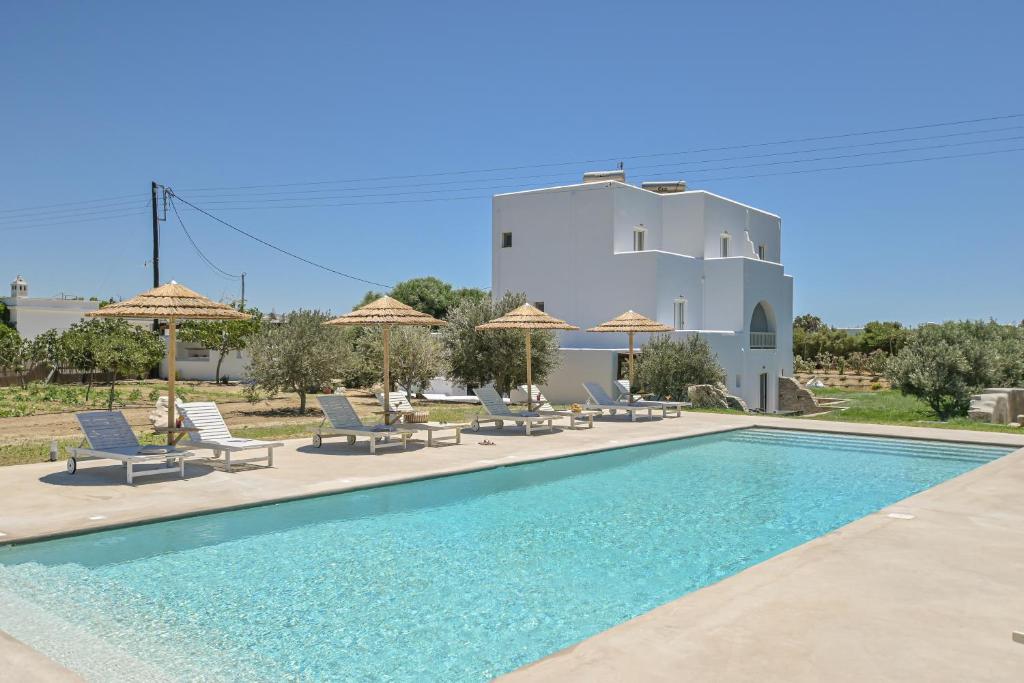 a pool with chairs and umbrellas in front of a building at Ktima Lino in Agia Anna Naxos