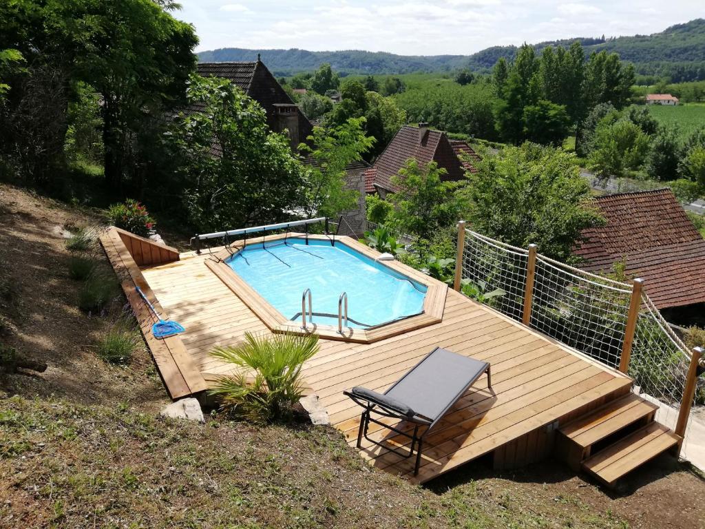 una terraza de madera con piscina y silla en Maison de charme en Périgord 10 personnes La maison d'Albertine, en Peyrillac-et-Millac