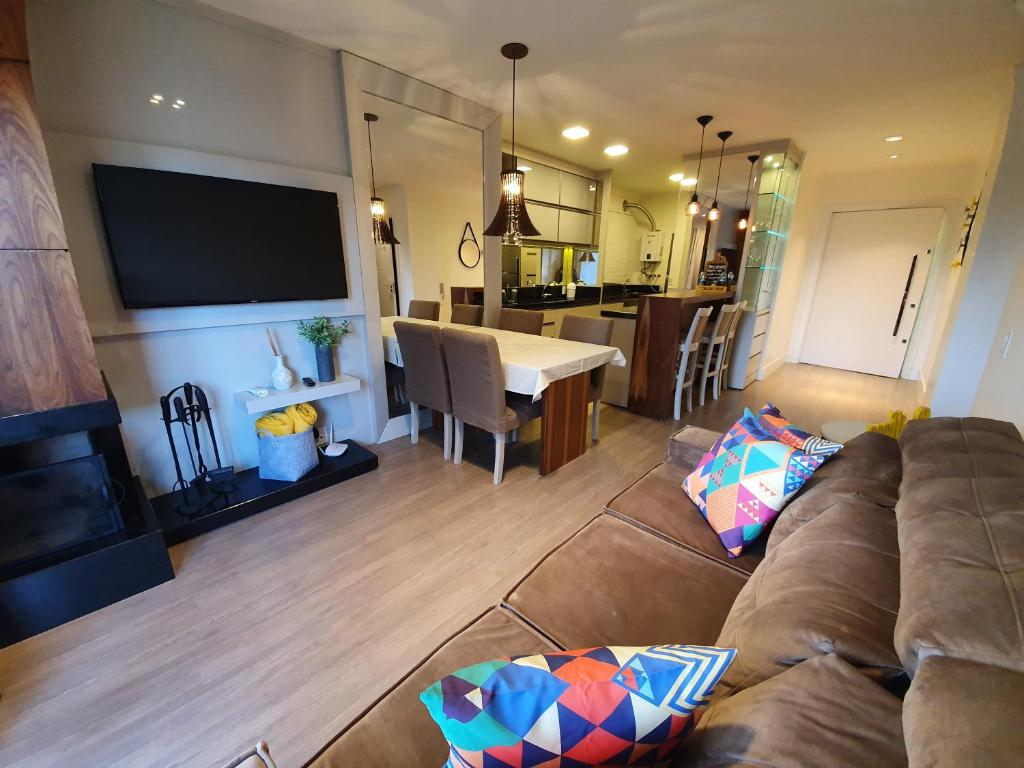 een woonkamer met een bank en een eetkamer bij Temporada Gramado e Canela - Apartamento Centro Campos de Canella in Canela