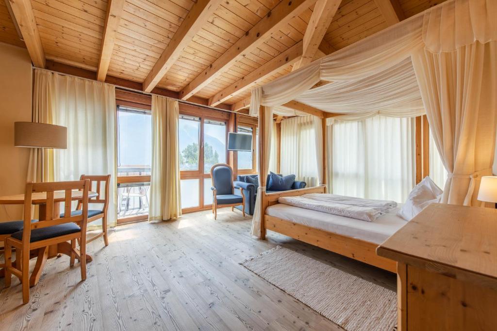 een slaapkamer met een bed, een tafel en stoelen bij Hotel Garni Zum Hirschen in Malles Venosta