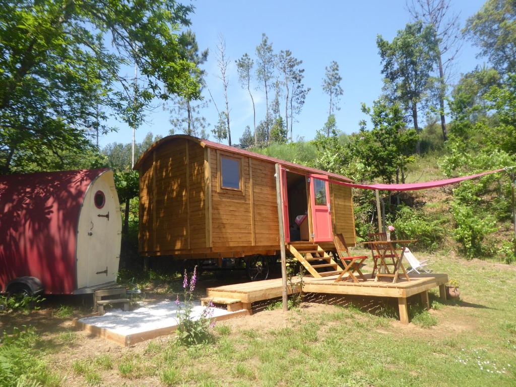 Une petite maison et une remorque dans un champ dans l'établissement Rosa the Cosy Cabin - Gypsy Wagon - Shepherds Hut, RIVER VIEWS Off-grid eco living, à Pedrógão Grande