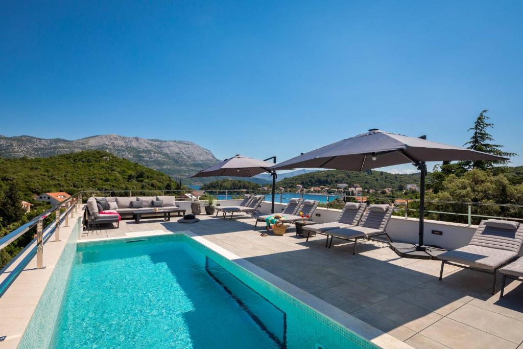 a swimming pool with chairs and umbrellas on a balcony at Villa Buddha Bay in Korčula