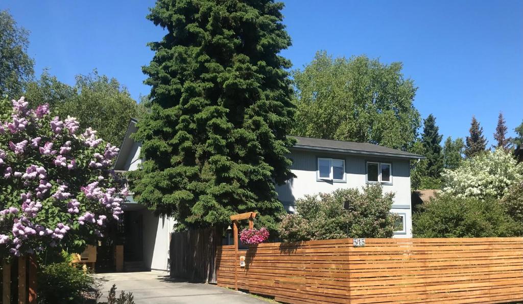 a house with a fence and a large tree at Gardenside Bed and Breakfast in Anchorage