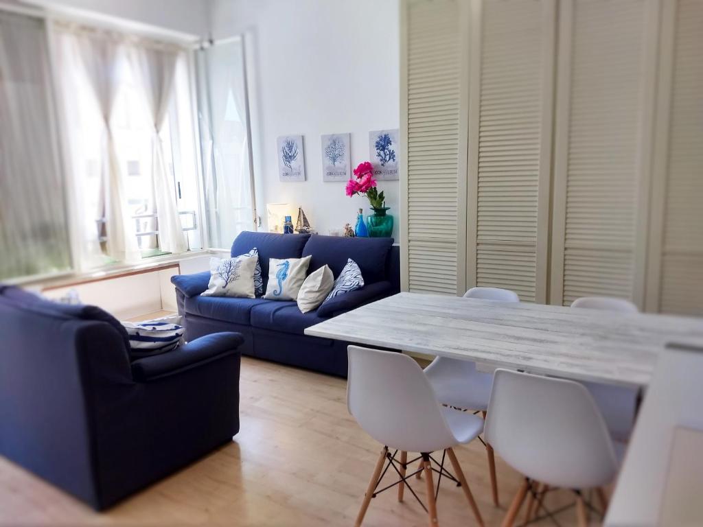 ein Wohnzimmer mit einem blauen Sofa, einem Tisch und Stühlen in der Unterkunft "Beach Cottage" monolocale vicino alla spiaggia in Chioggia