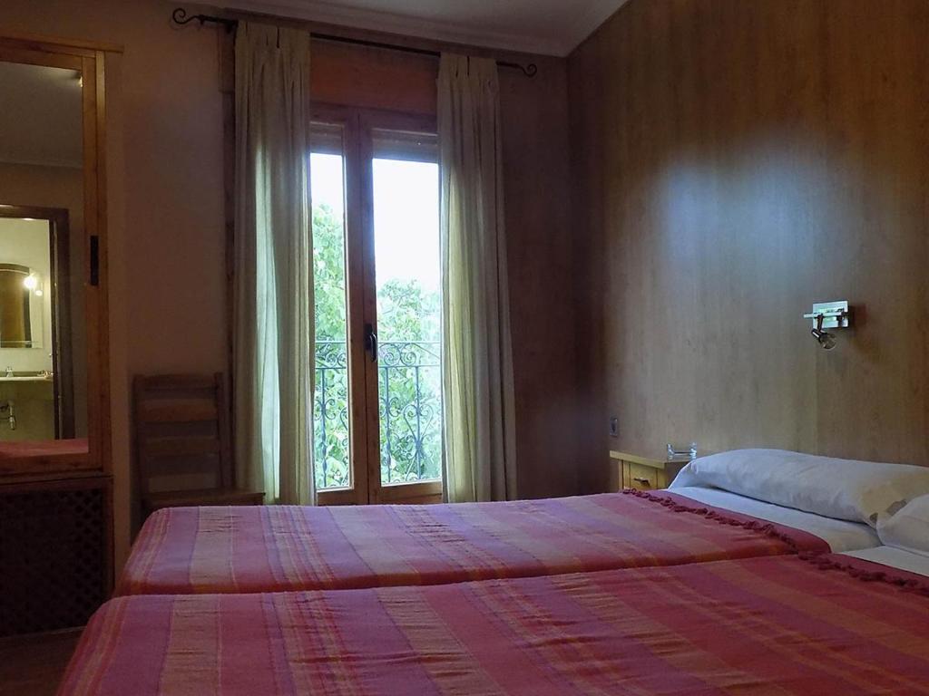 Un dormitorio con una cama grande y una ventana. en Hostal Los Palancares, en Fuentes