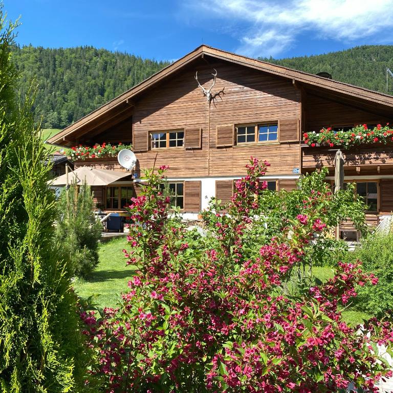 a wooden house with flowers in front of it at Chalet Tirolia in Kirchdorf in Tirol