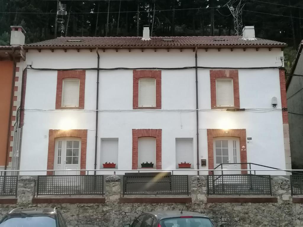 una casa blanca con ventanas y coches aparcados delante en Albergue Cervera de Pisuerga en Cervera de Pisuerga