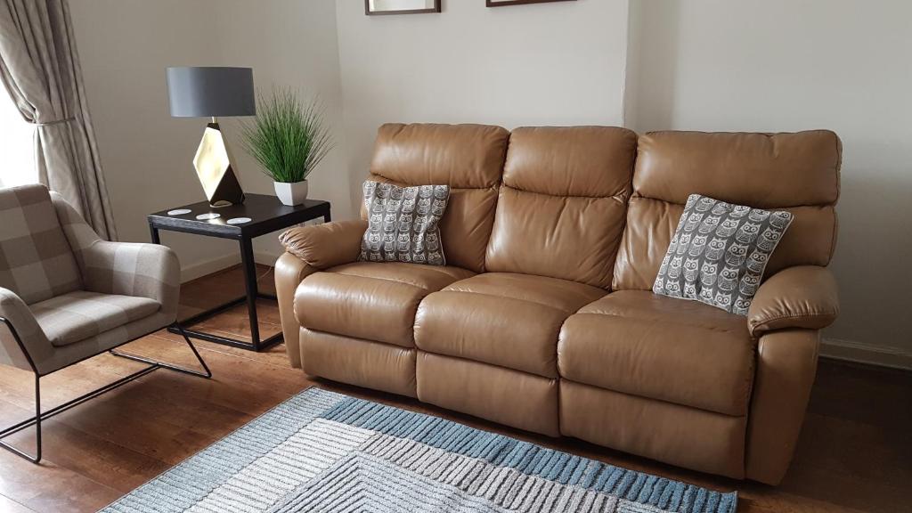 a brown leather couch in a living room with a chair at Old Town Edinburgh Apartment close to Castle and Royal Mile in Edinburgh