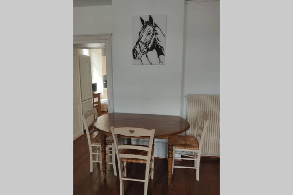 a dining room with a table and a horse picture on the wall at Grand appartement centre ville quartier calme in Neufchâteau