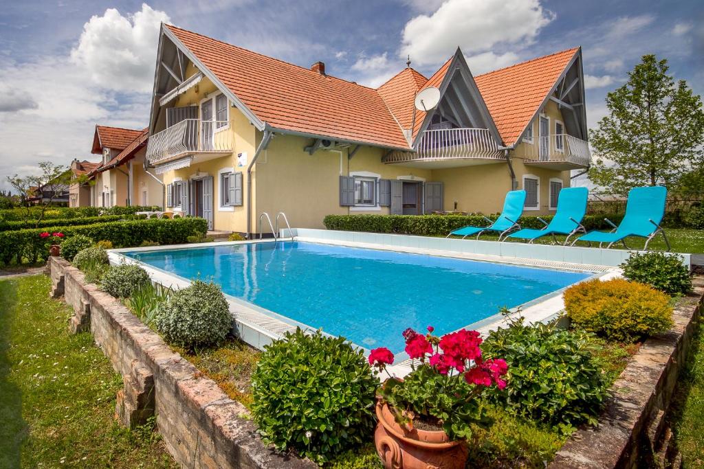 une maison avec une piscine entourée de chaises et de fleurs dans l'établissement Studio in Balatonmariafürdo 19236, à Balatonmáriafürdő