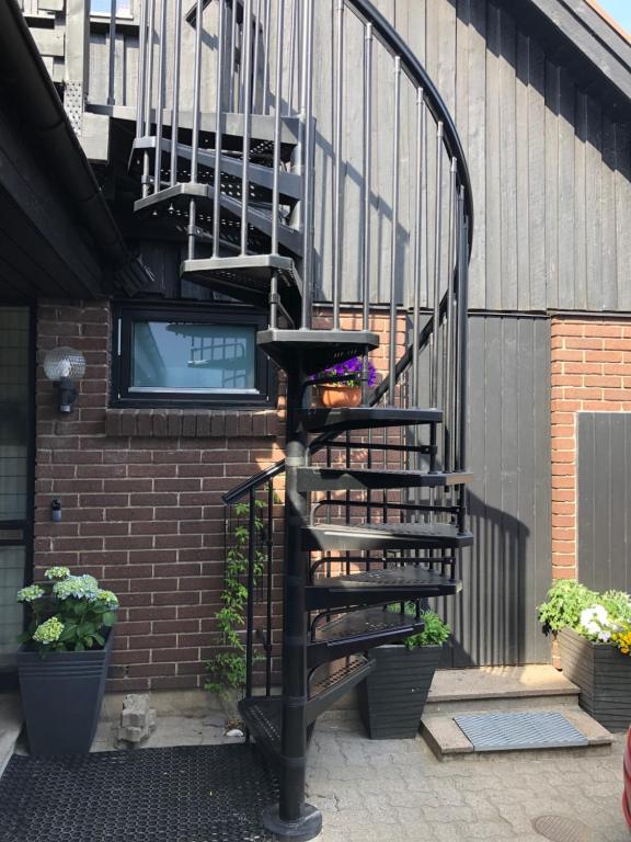 a spiral staircase next to a brick building with plants at En trappa upp in Malmö