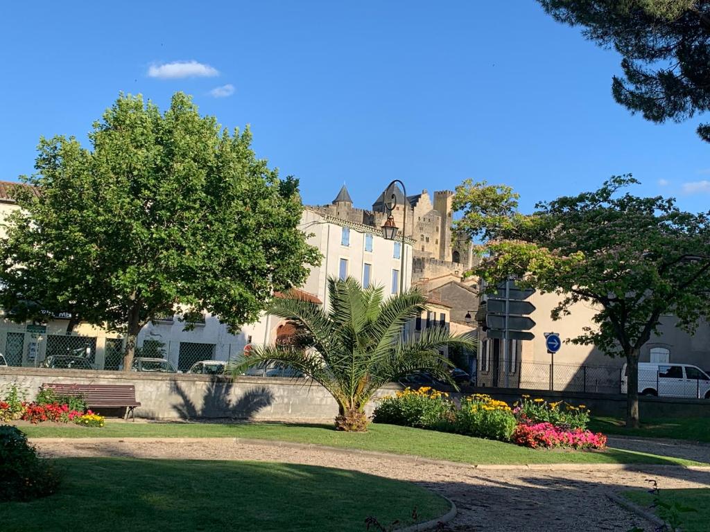 un parque con un edificio y árboles y flores en C’est une maison bleue en Carcassonne