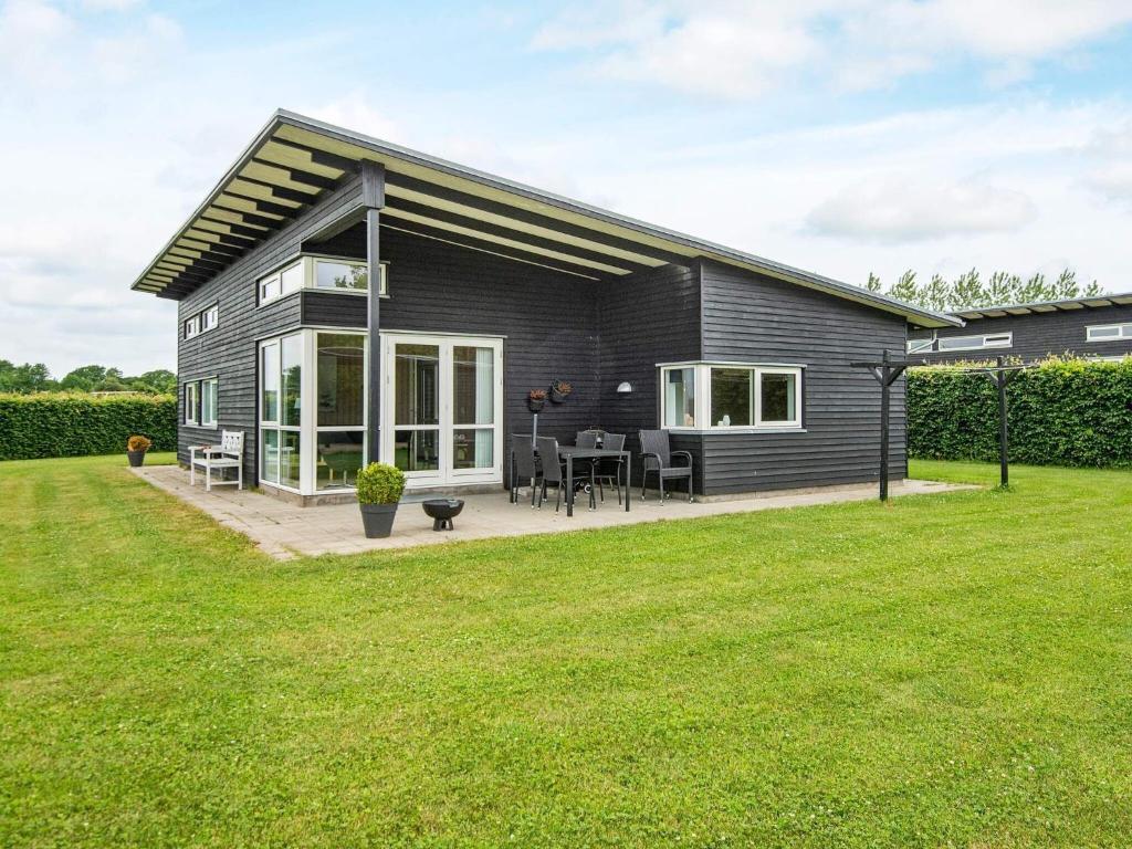 a black house with a patio and a lawn at 6 person holiday home in Haderslev in Årøsund