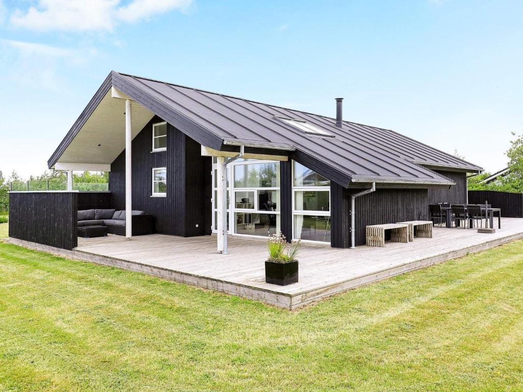 una casa negra con una gran terraza con mesas en 8 person holiday home in Brovst, en Brovst