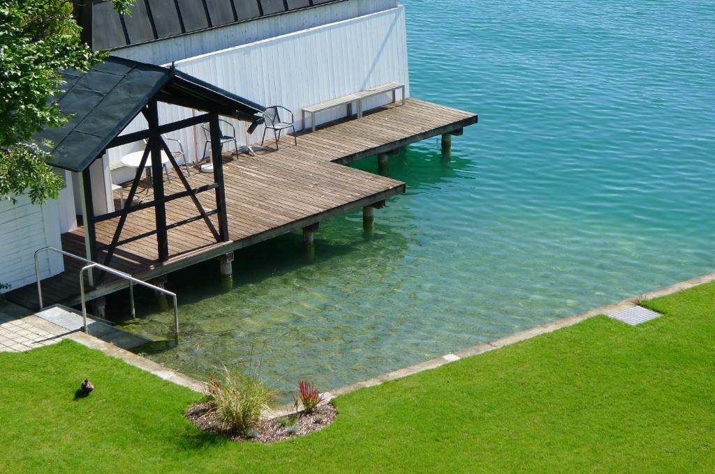 a wooden dock in the water next to a house at Seeappartement Marina in Pörtschach am Wörthersee